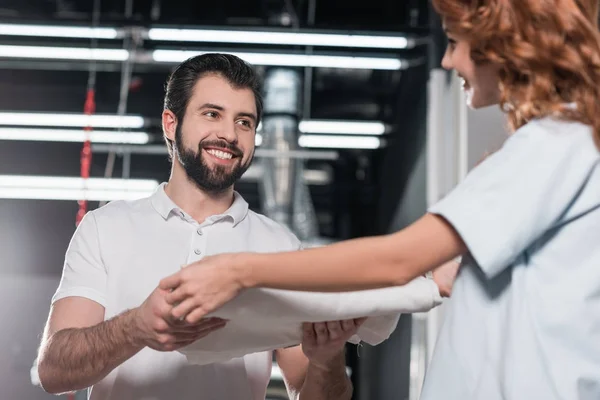 Felices jóvenes trabajadores de limpieza en seco pasando cloro limpio doblado - foto de stock