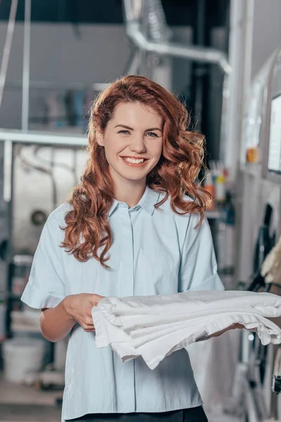 Mujer trabajadora de limpieza en seco sosteniendo pila de ropa blanca limpia — Stock Photo