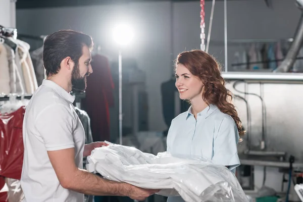 Young smiling dry cleaning workers at warehouse — Stock Photo