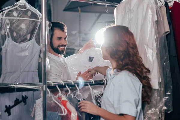 Young dry cleaning workers talking at warehouse — Stock Photo