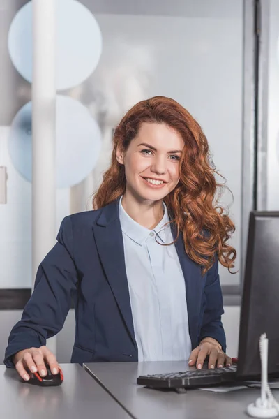 Giovane manager sorridente utilizzando il computer sul posto di lavoro — Foto stock