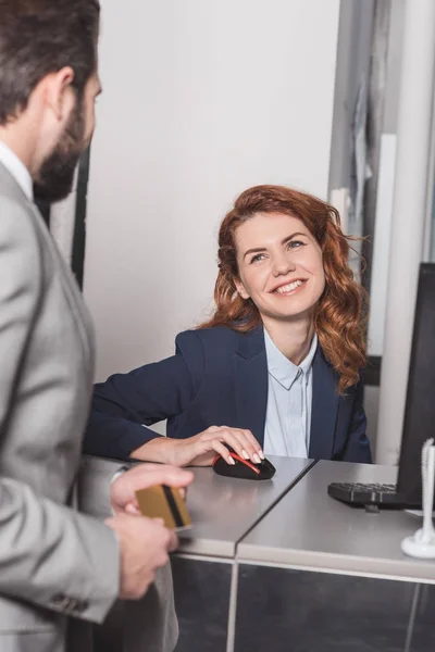 Bel homme tenant la carte de crédit au lieu de travail de caissier — Photo de stock