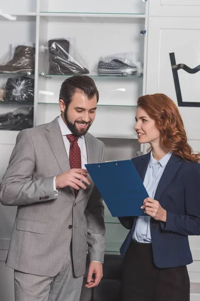 Lavaggio a secco manageress scrittura ordine di bel giovane — Foto stock