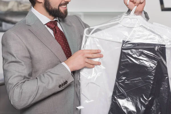 Cropped shot of businessman holding plastic bag of clean clothing — Stock Photo