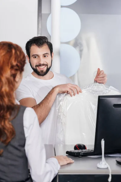 Smiling dry cleaning manager giving order to customer — Stock Photo