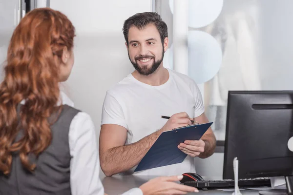 Dry cleaning manager writing orfer of customer — Stock Photo