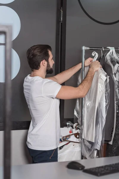 Trabalhador de limpeza a seco pendurando roupas no escritório — Fotografia de Stock