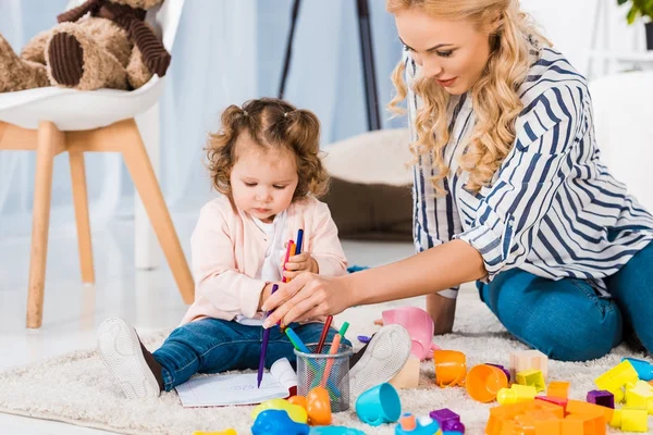 Giovane madre e bambino disegno insieme a casa — Foto stock