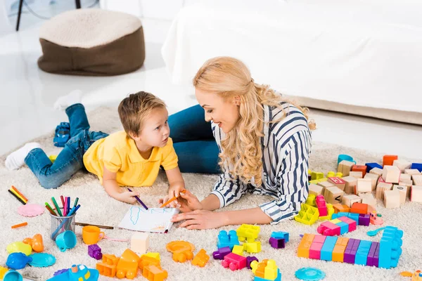 Jovem mãe ajudando filho ao desenhar juntos em casa — Fotografia de Stock