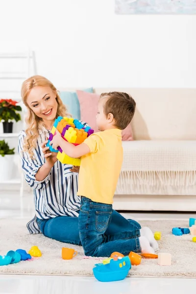 Mère et petit fils jouant avec des jouets ensemble sur le sol à la maison — Photo de stock