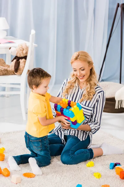 Mutter und kleiner Sohn spielen zu Hause gemeinsam mit Spielzeug auf dem Fußboden — Stockfoto