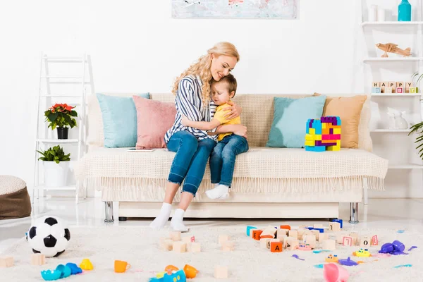 Sensual mother and little son hugging each other while resting on sofa at home — Stock Photo