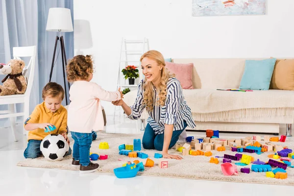 Mère heureuse et enfants jouant avec des blocs en plastique — Photo de stock