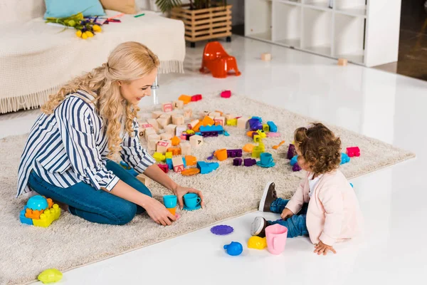 Sonrientes madre e hija jugando con vasos de plástico - foto de stock