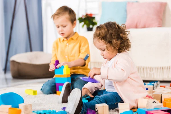 Adorable siblings playing on a floor with plastic blocks — Stock Photo