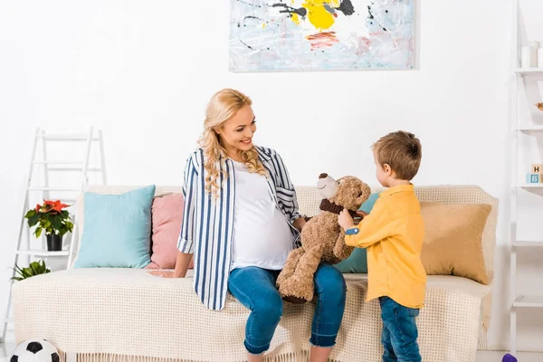 Smiling pregnant mother presenting son teddy bear — Stock Photo