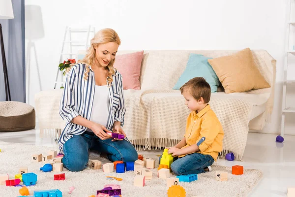 Embarazada madre jugando plástico bloques con hijo - foto de stock