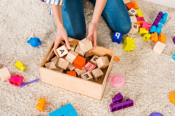 Cropped image of woman collecting children toys — Stock Photo