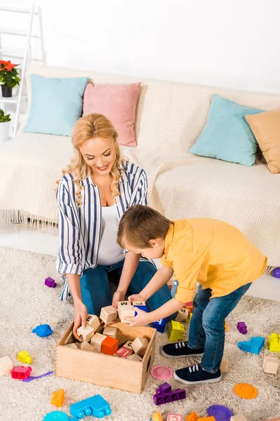 Happy mother and son looking at wooden cubes — Stock Photo