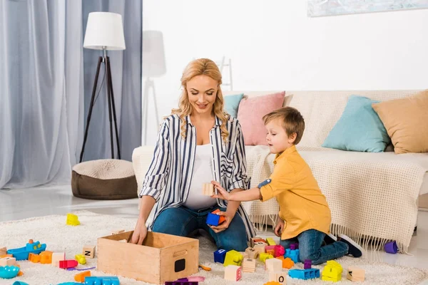 Son showing wooden cube to smiling mother — Stock Photo