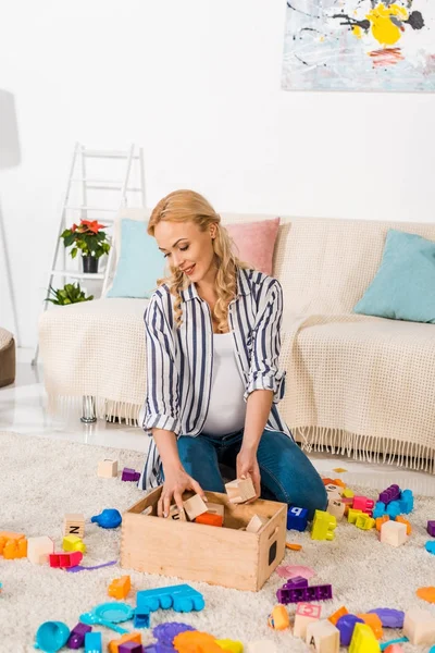 Embarazada mujer coleccionando niños juguetes - foto de stock