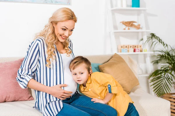 Hijo escuchando embarazada madre vientre - foto de stock