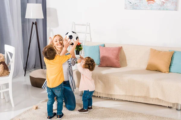 Happy mother and adorable little kids holding soccer ball at home — Stock Photo