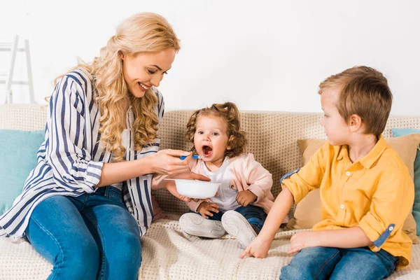 Smiling mother feeding cute little daughter at home — Stock Photo