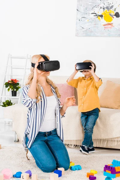 Belle mère et son fils en utilisant des casques de réalité virtuelle ensemble à la maison — Photo de stock