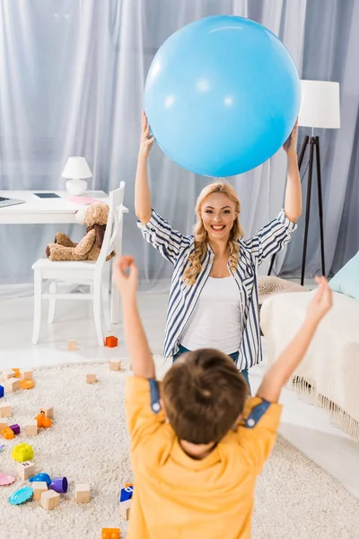 Feliz madre e hijo jugando con la pelota de fitness juntos en casa - foto de stock