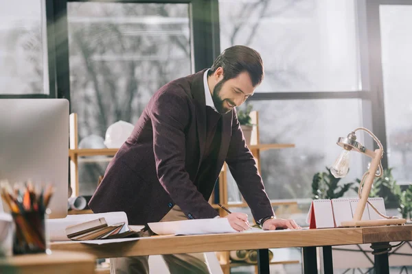 Schöner Architekt arbeitet mit Entwürfen in modernem Büro — Stockfoto