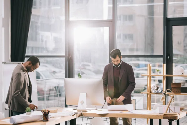 Arquitectos multiculturales que trabajan en oficinas modernas - foto de stock