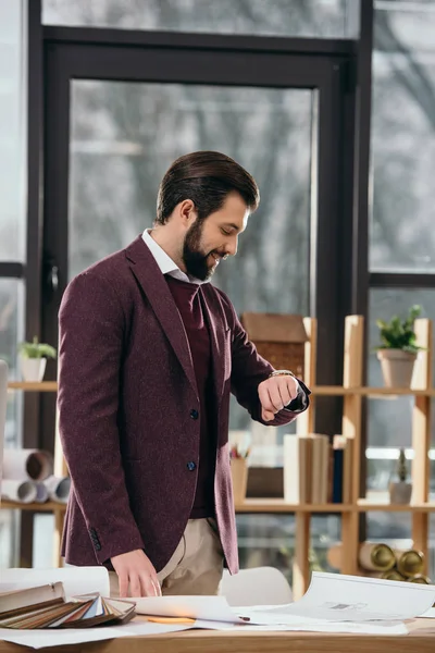 Handsome architect looking at wristwatch in modern office — Stock Photo
