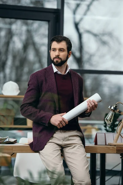 Thoughtful architect holding blueprint in modern office — Stock Photo
