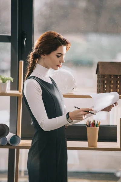 Architetto donna che lavora con cianografie alla finestra in ufficio — Foto stock