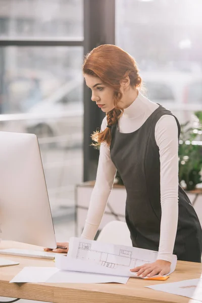 Architetto donna che lavora con cianografie e computer in ufficio — Foto stock