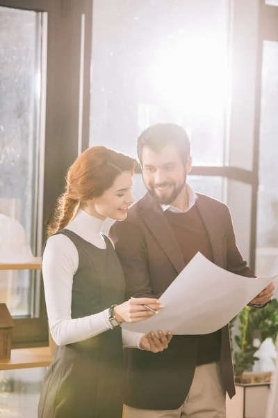 Two architects working with blueprint in office with back light — Stock Photo