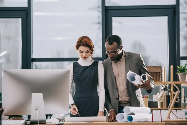 Architectes multiethniques discutant des plans sur le lieu de travail — Photo de stock