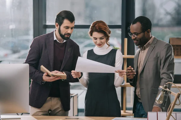 Arquitectos multiétnicos discutiendo el proyecto en la oficina moderna - foto de stock