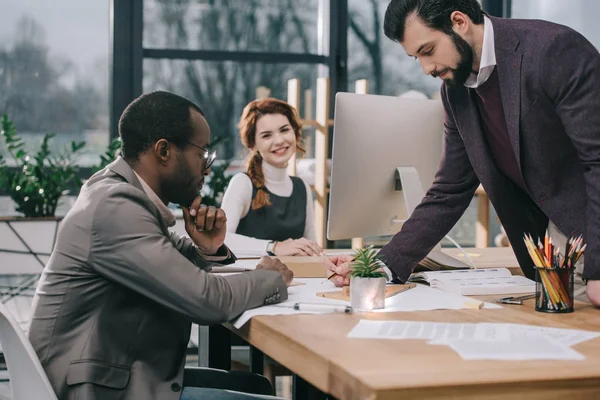 Arquitectos multiétnicos discutiendo planes de construcción en la oficina - foto de stock