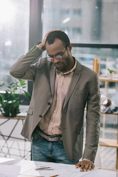 Pensive african american architect looking at building plans — Stock Photo