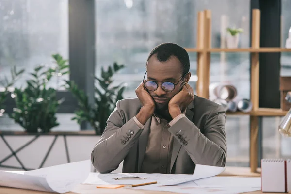 Thoughtful african american architect looking at blueprints in office — Stock Photo