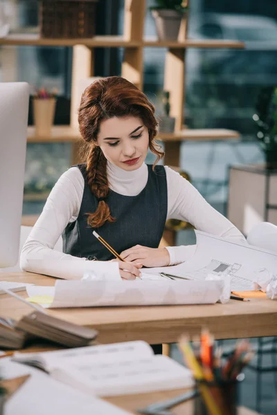 Female architect drawing blueprints with pencil and compasses — Stock Photo