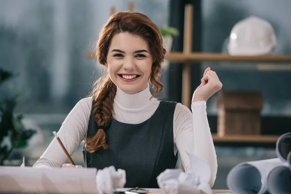 Cheerful female architect drawing building plans in office — Stock Photo