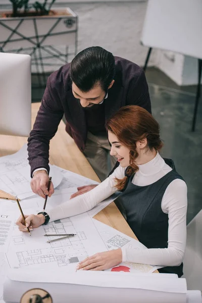 Arquitectos que trabajan con planos en el lugar de trabajo en la oficina moderna - foto de stock