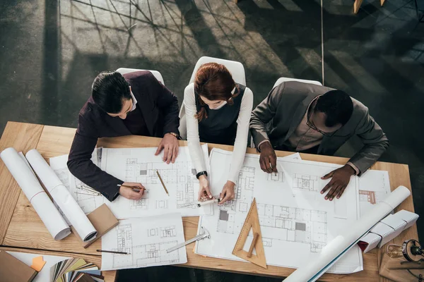 Blick aus der Vogelperspektive auf das Architektenteam, das mit den Plänen im Büro zusammenarbeitet — Stockfoto