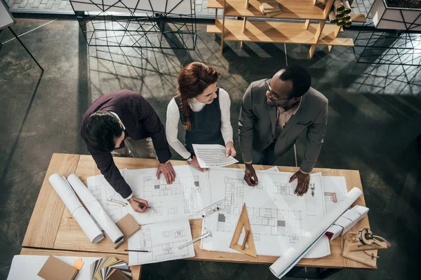 Blick aus der Vogelperspektive auf das Architektenteam, das im Büro mit Bauplänen arbeitet — Stockfoto