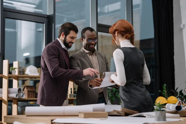Heureuse équipe multiethnique d'architectes discutant de documents au bureau — Photo de stock