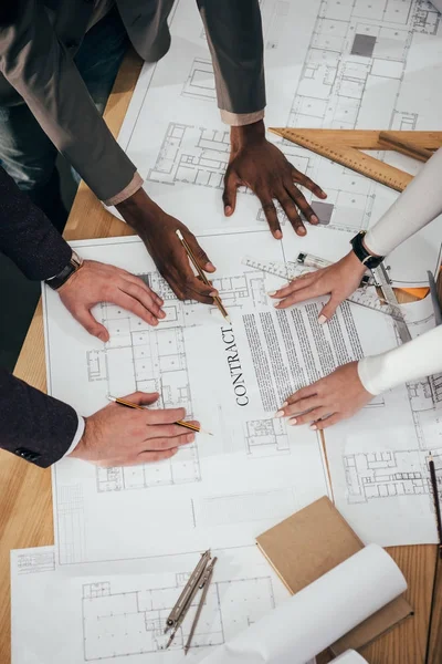 Tiro recortado de equipe de arquitetos que trabalham em conjunto com contrato e planos de construção — Fotografia de Stock