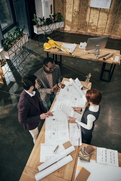 Vue en grand angle de l'équipe d'architectes discutant des plans de construction — Photo de stock